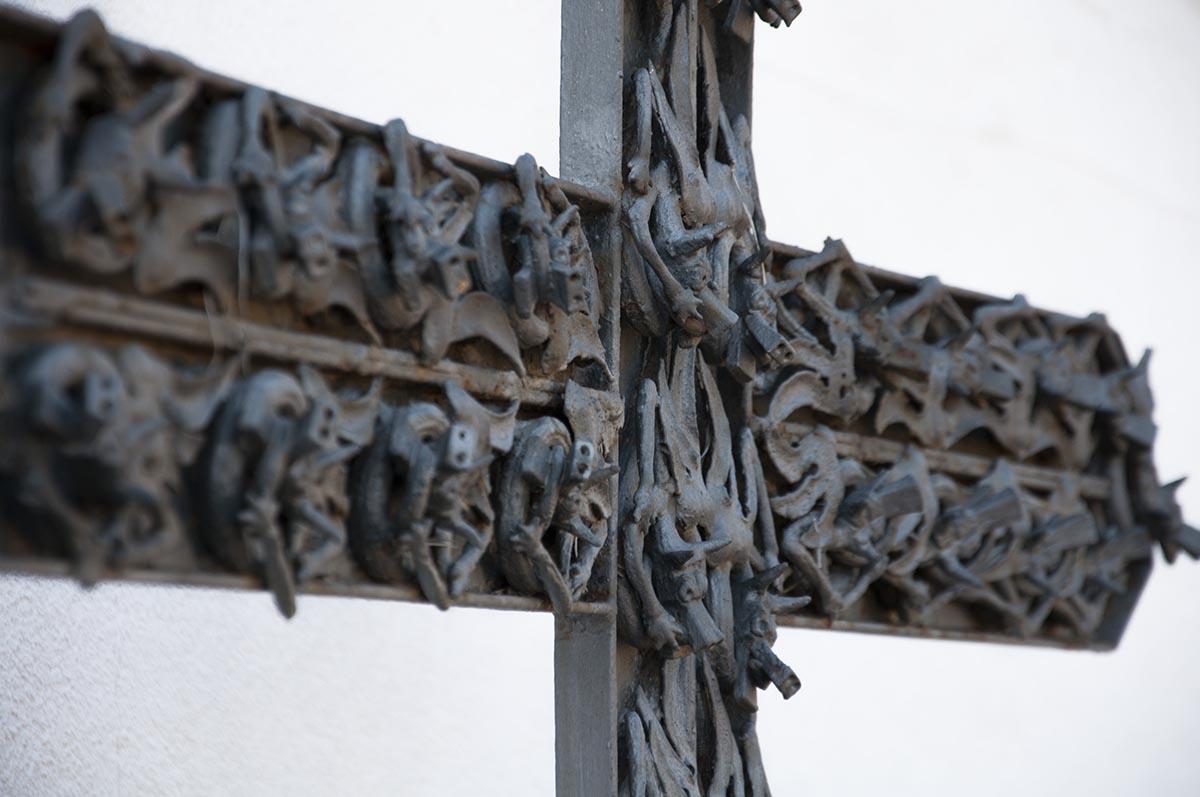 Detall d’una creu en ferro forjat recoberta de petits dracs.