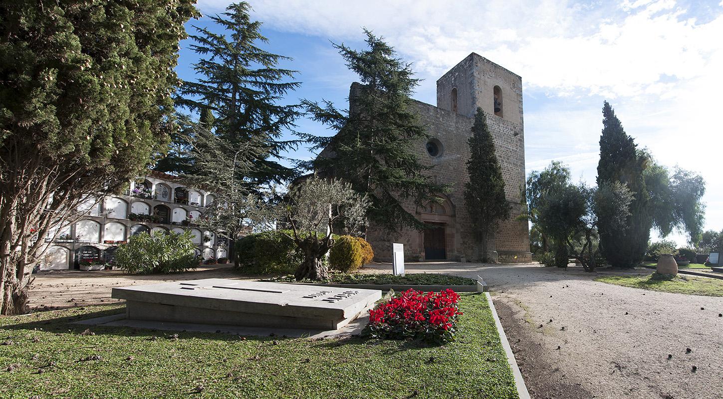 Vista de la primitiva església parroquial de Sant Andreu. En primer pla podem veure una tomba amb un acurat enjardinament.