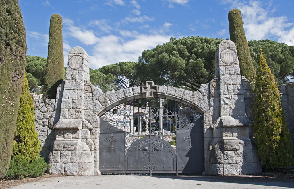 Imponent porta d’entrada al cementiri realitzada en granit gris i completada amb un barri de ferro forjat obra de l’artesà local Joan Codina Bramona.